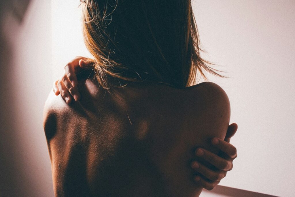 Dos nu d'une femme, une main posée sur l'épaule