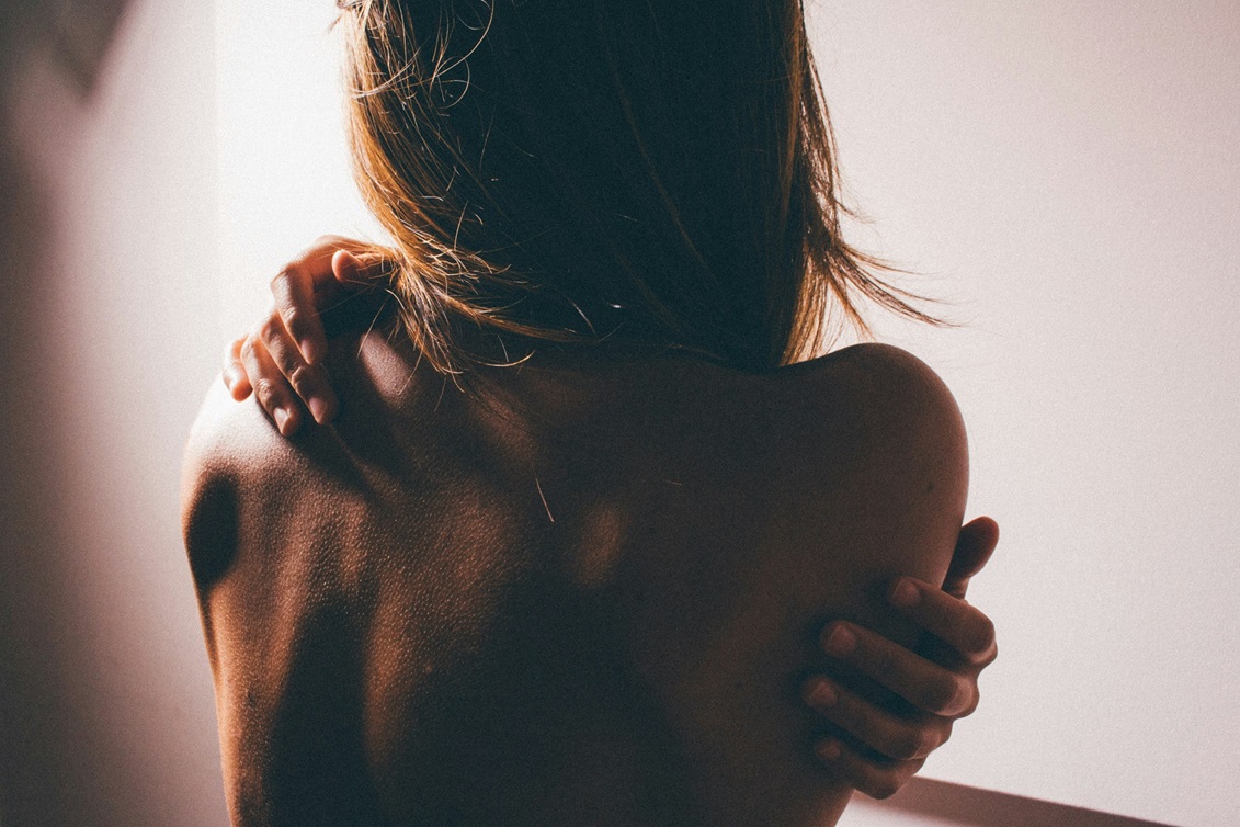 Dos nu d'une femme, une main posée sur l'épaule