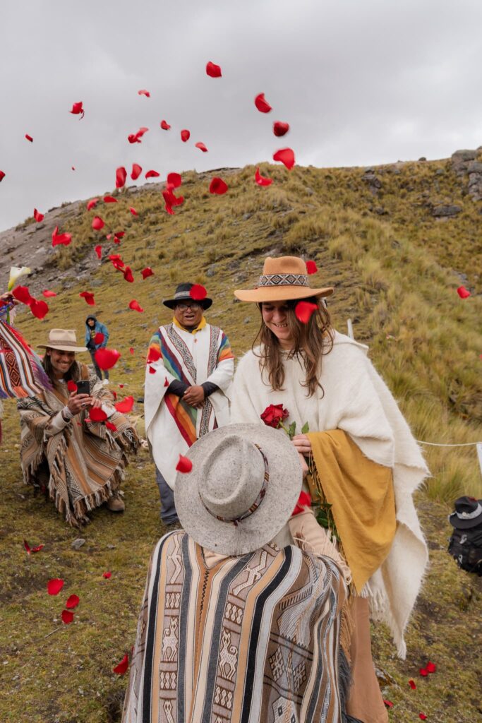 Groupe en ponchos sur une colline des Andes sous une pluie de pétales de roses
